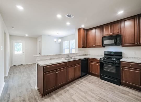 a kitchen with wooden cabinets and black appliances at The Village at Caney Mills, Conroe, TX, 77303