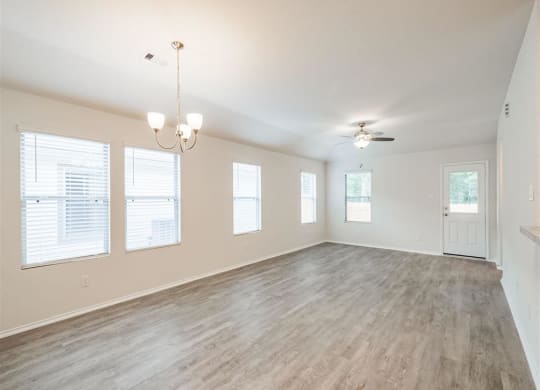 an empty living room with a ceiling fan and windows at The Village at Caney Mills, Conroe, Texas