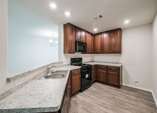 a kitchen with wooden cabinets and granite counter tops at The Village at Caney Mills, Texas, 77303