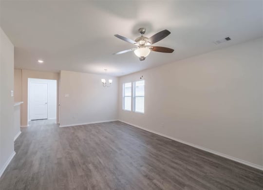 an empty living room with a ceiling fan and a window at The Village at Caney Mills, Conroe, 77303