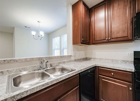 a kitchen with a stainless steel sink and wooden cabinets at The Village at Caney Mills, Conroe