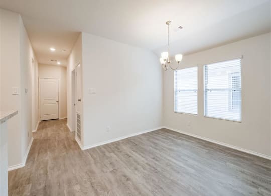 the living room and dining room of an empty home with wood flooring at The Village at Caney Mills, Conroe, Texas