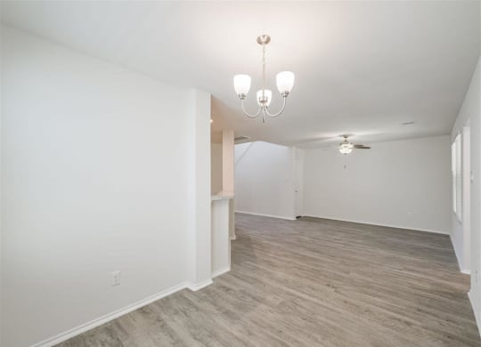 the living room and dining room in a new home with white walls and wood floors at The Village at Caney Mills, Conroe, Texas