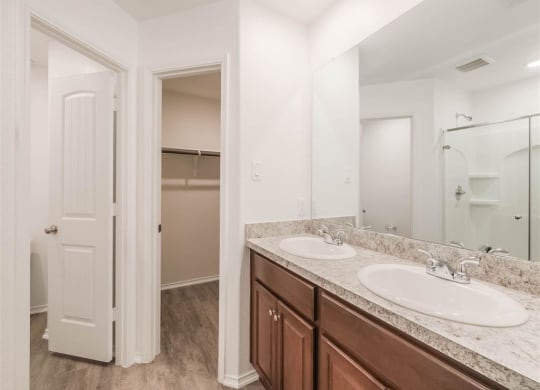 a bathroom with two sinks and a mirror at The Village at Caney Mills, Texas, 77303