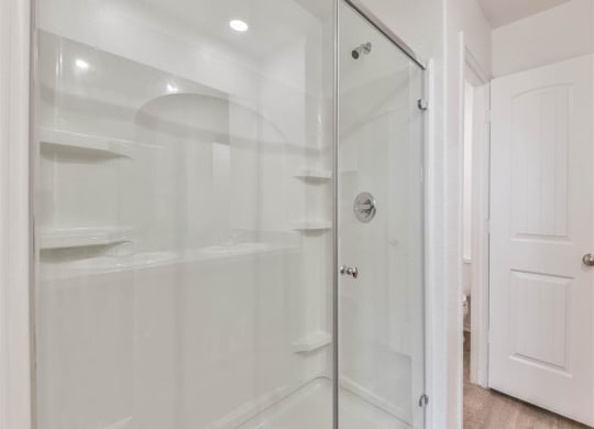 a white bathroom with a glass shower door at The Village at Caney Mills, Texas