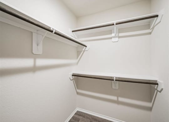 a spacious walk in closet with white walls and a hanging rack at The Village at Caney Mills, Conroe, TX, 77303