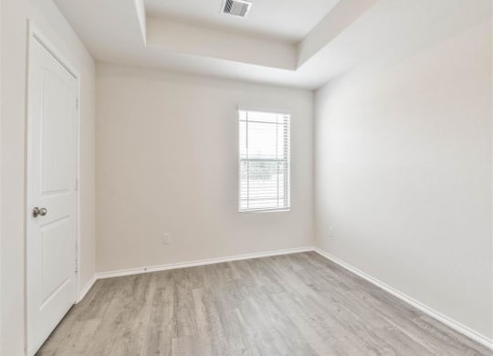 an empty room with white walls and wood flooring and a window at The Village at Caney Mills, Conroe, TX, 77303