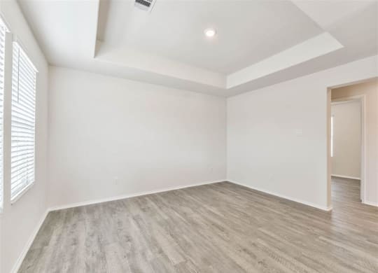 an empty living room with white walls and wood flooring at The Village at Caney Mills, Texas