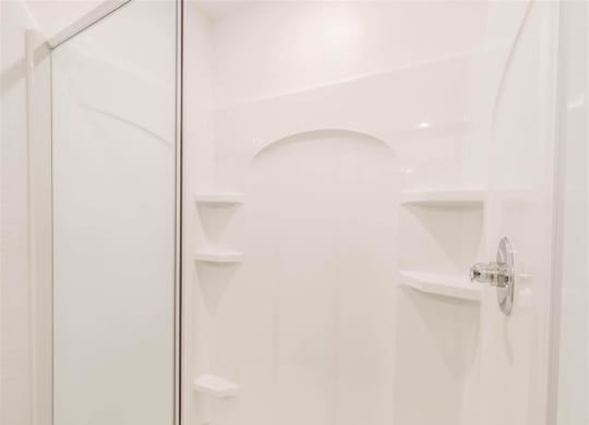 a white bathroom with a shower and shelves in it at The Village at Caney Mills, Conroe