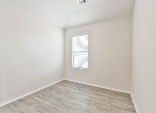 an empty room with a window and wood flooring at The Village at Caney Mills, Texas, 77303