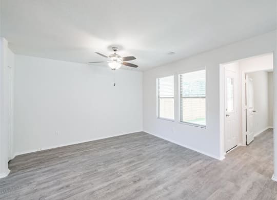 an empty living room with a ceiling fan and a window at The Village at Caney Mills, Conroe