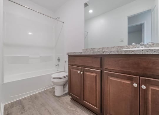 a bathroom with wooden cabinets and a toilet and a shower at The Village at Caney Mills, Conroe, Texas