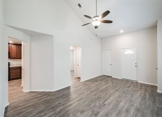the living room and kitchen of a new home with a ceiling fan at The Village at Caney Mills, Conroe, 77303