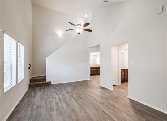 an empty living room with white walls and a ceiling fan at The Village at Caney Mills, Texas, 77303