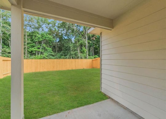 a covered porch overlooking a lawn and a wood fence at The Village at Caney Mills, Conroe, Texas