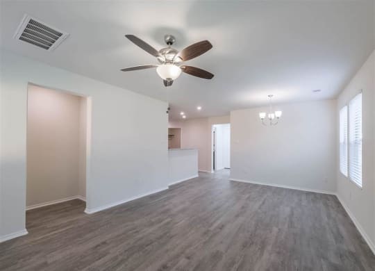 an empty living room with a ceiling fan and a kitchen at The Village at Caney Mills, Conroe, Texas
