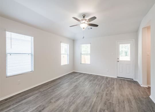an empty living room with a ceiling fan and a door at The Village at Caney Mills, Conroe, TX, 77303
