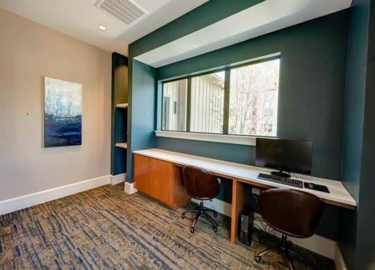 a room with a desk with a computer and a window
