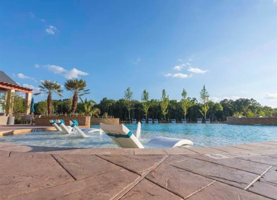 a swimming pool with lounge chairs on a wooden deck