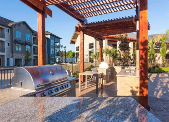 a covered patio with a grill and a table with chairs