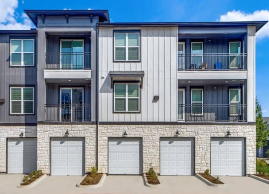 an exterior view of an apartment building with three garage doors