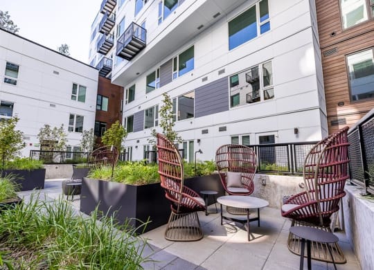 a patio with chairs and a table in front of an apartment building