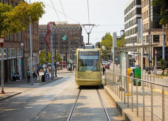 a yellow tram traveling down a street next to tall buildings