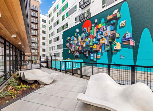 a large mural on the side of a building with two benches in front of it