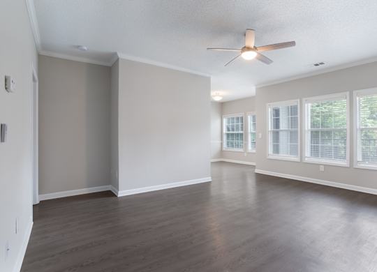Empty room with a ceiling fan and large windows.
