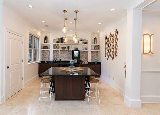a kitchen with white walls and tiles flooring and a large center island with a black counter at Westmount at Ashwood, Georgia