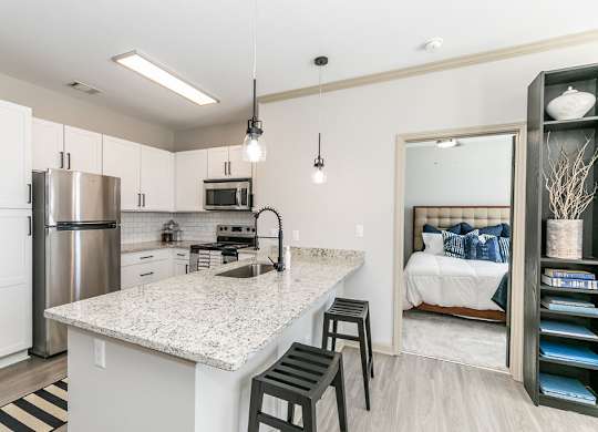 a kitchen with a breakfast bar and a bedroom in the background at Westmount at Ashwood, Georgia