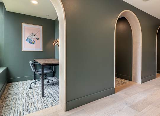 an arched doorway leading into a home office with a desk and chair