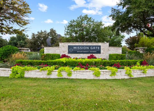 Welcoming Gate surrounded by grass and well manicured landscaping at Mission Gate in Plano TX