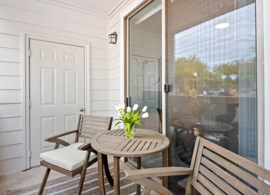a small porch with a table and chairs and a sliding glass door at Mission Gate, Texas, 75024