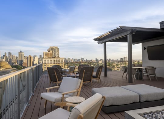 a balcony with a view of a city skyline and a deck with chairs and tables at the Belden Stratford in Chicago, IL