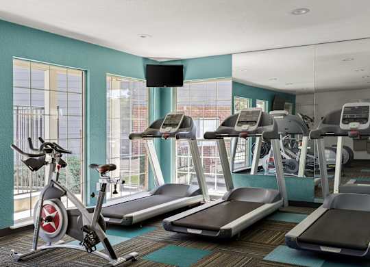 a gym with treadmills and exercise bikes in a room with windows  at Verona, Littleton, CO, 80123