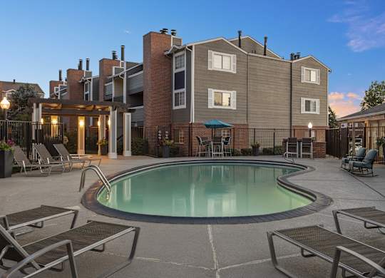 a swimming pool with chairs and a building in the background  at Verona, Colorado, 80123