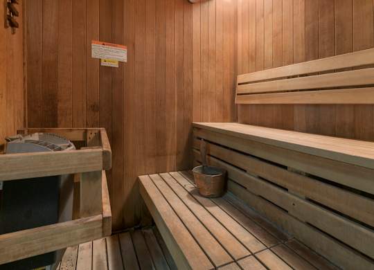 A wooden sauna with benches and a bucket.