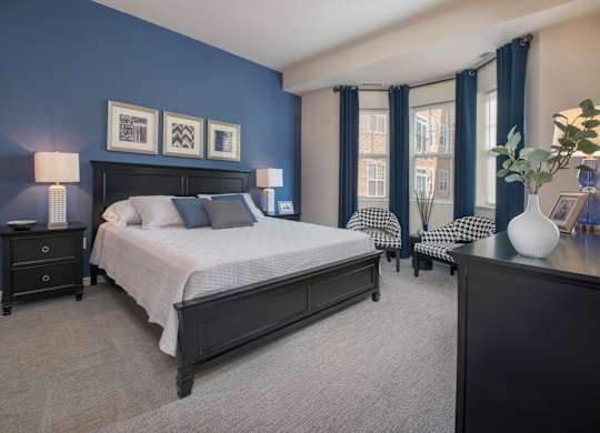 A bedroom with a large bed and a nightstand with a lamp.