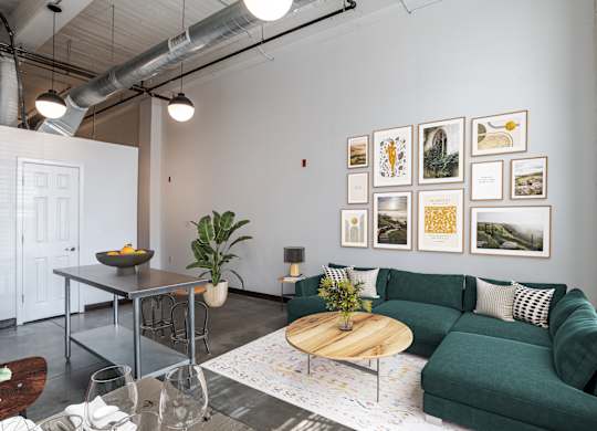 a modern living room with a green couch, a coffee table, and pictures on the wall at Highland Mill Lofts in Charlotte, NC  28204