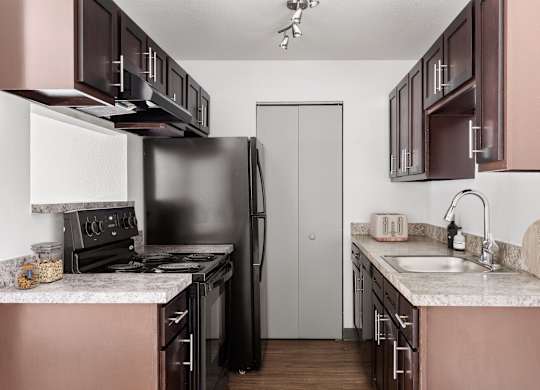 a kitchen with black appliances and white counter tops and brown cabinets  at Verona, Littleton, CO, 80123