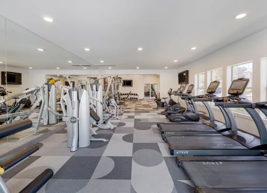 a gym with cardio equipment and weights on a checkered floor at Paisley and Pointe Apartments, Las Vegas, Nevada