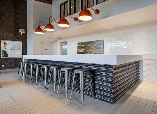 a long bar with stools in front of a white counter in a hotel lobby at Ashford Belmar Apartments, Lakewood, Colorado