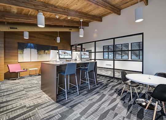an open office space with tables and chairs and a bar with chairs at Ashford Belmar Apartments, Lakewood, CO 80226