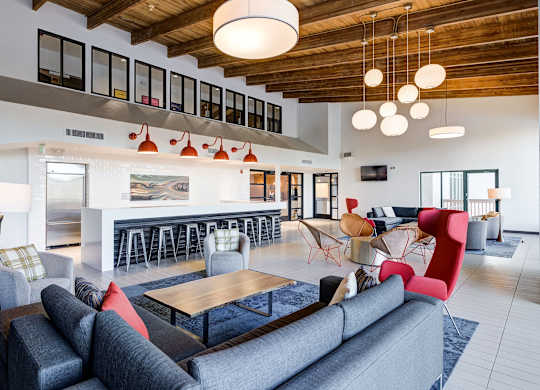 a living room with couches and chairs and a kitchen at Ashford Belmar Apartments, Lakewood, CO