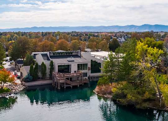 an aerial view of a house on a lake with mountains in the background at Ashford Belmar Apartments, Lakewood, CO 80226