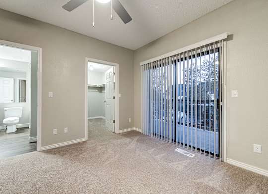 an empty living room with a large window and a ceiling fan at Ashford Belmar Apartments, Lakewood, CO