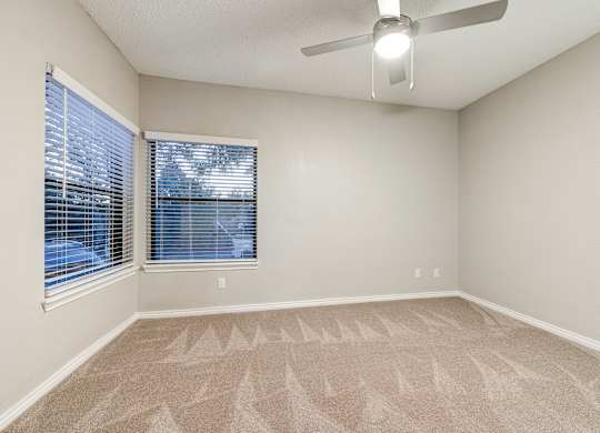 an empty living room with a large window and a ceiling fan at Ashford Belmar Apartments, Lakewood, 80226
