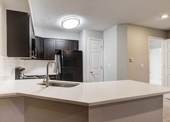 an empty kitchen with a sink and a refrigerator at Ashford Belmar Apartments, Colorado, 80226