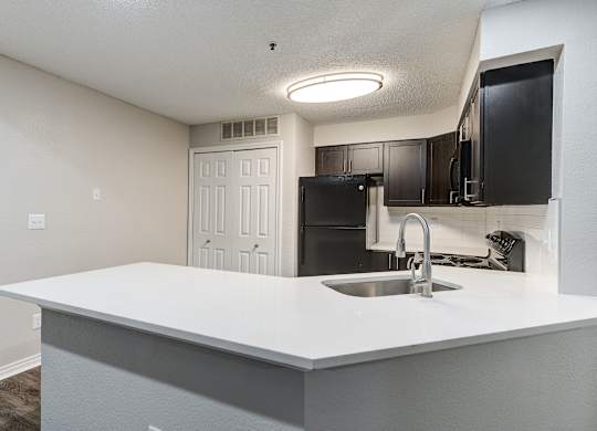an empty kitchen with a sink and a refrigerator at Ashford Belmar Apartments, Colorado